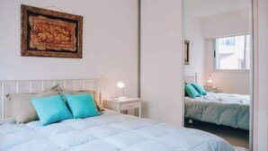 A bedroom with a bed, a nightstand, a lamp, a mirror, and a painting on the wall. - Puerto Pileta Grill and Garage on the Peninsula (Punta del Este)