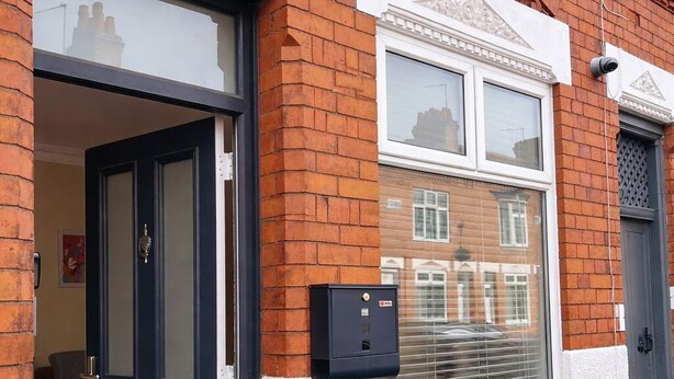 A residential building with a dark blue door, white-framed windows, and a white textured wall. - Entire Excellent Property on Mountcastle Road, Leicester (Leicester)
