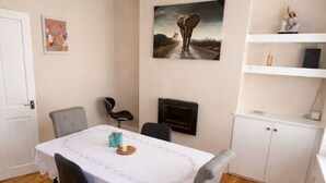A dining area with a table, chairs, a fireplace, and a shelf with decorative items. - Entire Excellent Property on Mountcastle Road, Leicester (Leicester)
