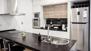 A modern kitchen with stainless steel appliances, a black countertop, and a built-in oven. - Renovated house Premium kitchen 3 Bed. Grill (Paraná)