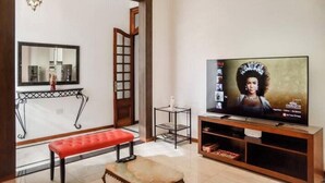 A living room with a television, a red bench, a small table, and a decorative mirror. - Renovated house Premium kitchen 3 Bed. Grill (Paraná)