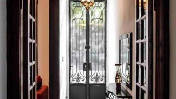 A hallway with a black door featuring a decorative glass panel and a chandelier above. - Renovated house Premium kitchen 3 Bed. Grill (Paraná)