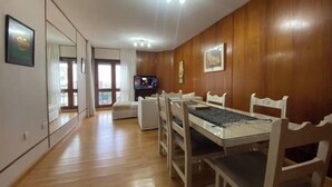 A dining area with a wooden table and chairs, a television, and a large mirror on the wall. - Beautiful 10th Floor Quality Full Park Zone (Paraná)