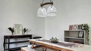 Un espace repas avec une table en bois, des bancs et un lustre.