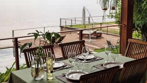 Une table à manger dressée pour six personnes, avec vue sur une étendue d’eau calme.
