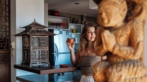 Une cuisine avec une lanterne décorative, un réfrigérateur et une personne tenant une tasse.