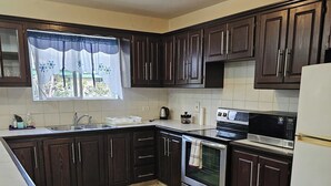 Una cocina con armarios de madera oscura, un lavamanos de acero inoxidable, una estufa y un refrigerador.