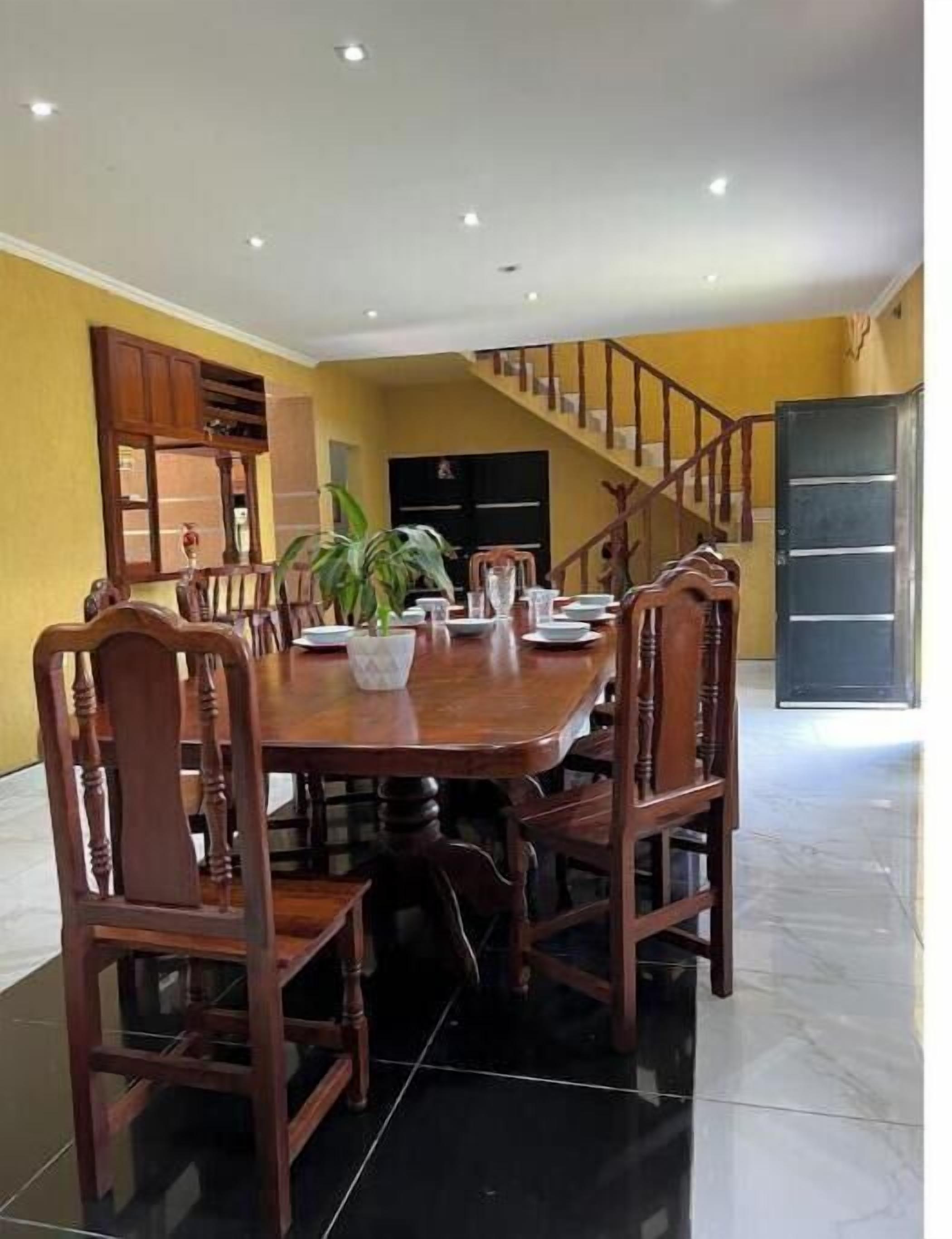 A dining area with a round table, wooden chairs, and a potted plant.