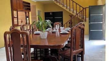 A dining area with a round table, wooden chairs, and a potted plant.