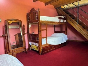 Quarto com uma cama beliche, um guarda-roupa de madeira, um espelho e uma escada.