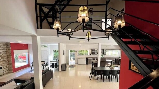 A spacious living area with a staircase, a dining area, and a kitchen visible in the background. - Beautiful Quinta House for 12 people very spacious (Entre Ríos)