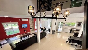 A spacious living area with a modern kitchen, a large TV, and a staircase leading to an upper level. - Beautiful Quinta House for 12 people very spacious (Entre Ríos)