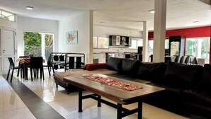A spacious living area with a large sofa, a dining table with chairs, and a kitchen in the background. - Beautiful Quinta House for 12 people very spacious (Entre Ríos)