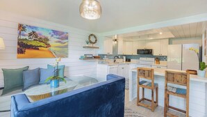 A modern kitchen with white cabinets, a central island, and wooden chairs.