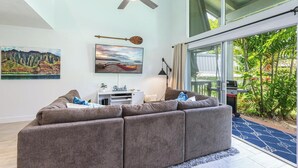 A modern living room with a large sectional sofa, a ceiling fan, and artwork on the walls.