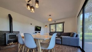 Una sala de estar moderna con comedor, chimenea y un amplio ventanal con vistas al exterior.
