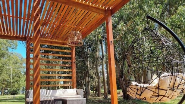 Una pérgola de madera con una silla colgante y un columpio.