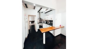 Une cuisine moderne avec des meubles blancs, un plan de travail en bois et un sol noir.