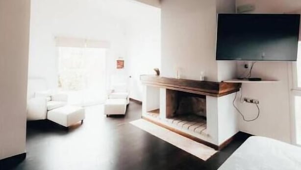 Une chambre moderne dotée d’une cheminée, d’un téléviseur à écran plat fixé au mur et d’une grande fenêtre laissant entrer la lumière naturelle.
