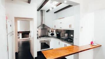 Une cuisine moderne avec des meubles blancs, un plan de travail en bois et un sol noir.