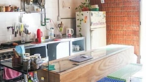 Une cuisine moderne avec un îlot central en bois, des luminaires suspendus et un mur en briques.