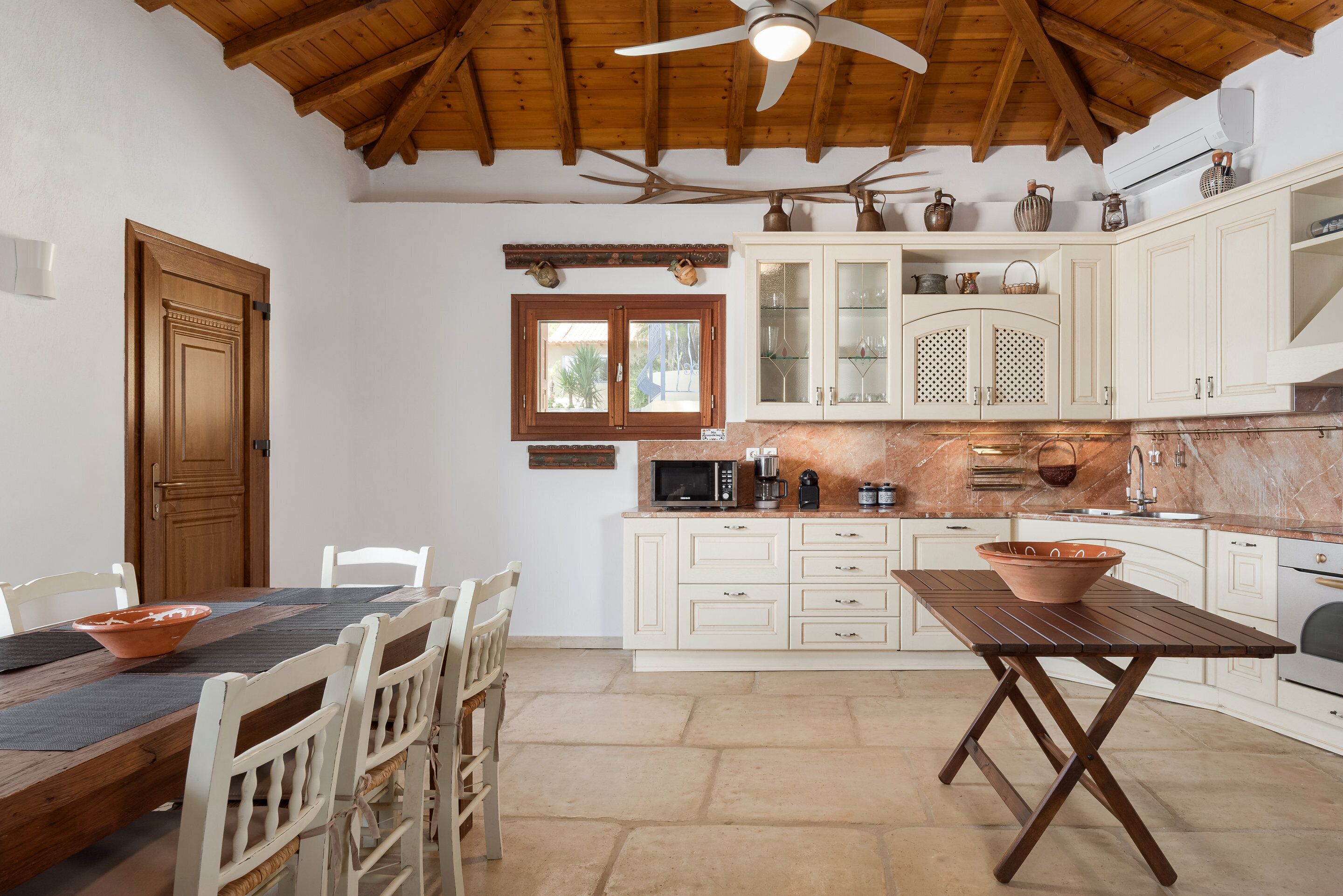 A kitchen with white cabinets, a wooden ceiling, and a dining area with a table and chairs.