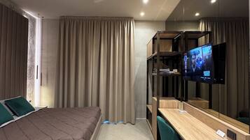 Quarto de hotel moderno com cama, escrivaninha, televisão e guarda-roupa.
