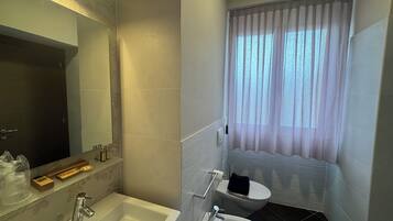 A bathroom with a bathtub, toilet, and a large mirror.