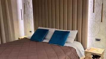 A modern bedroom with a large bed, a wooden headboard, and a nightstand with a lamp.