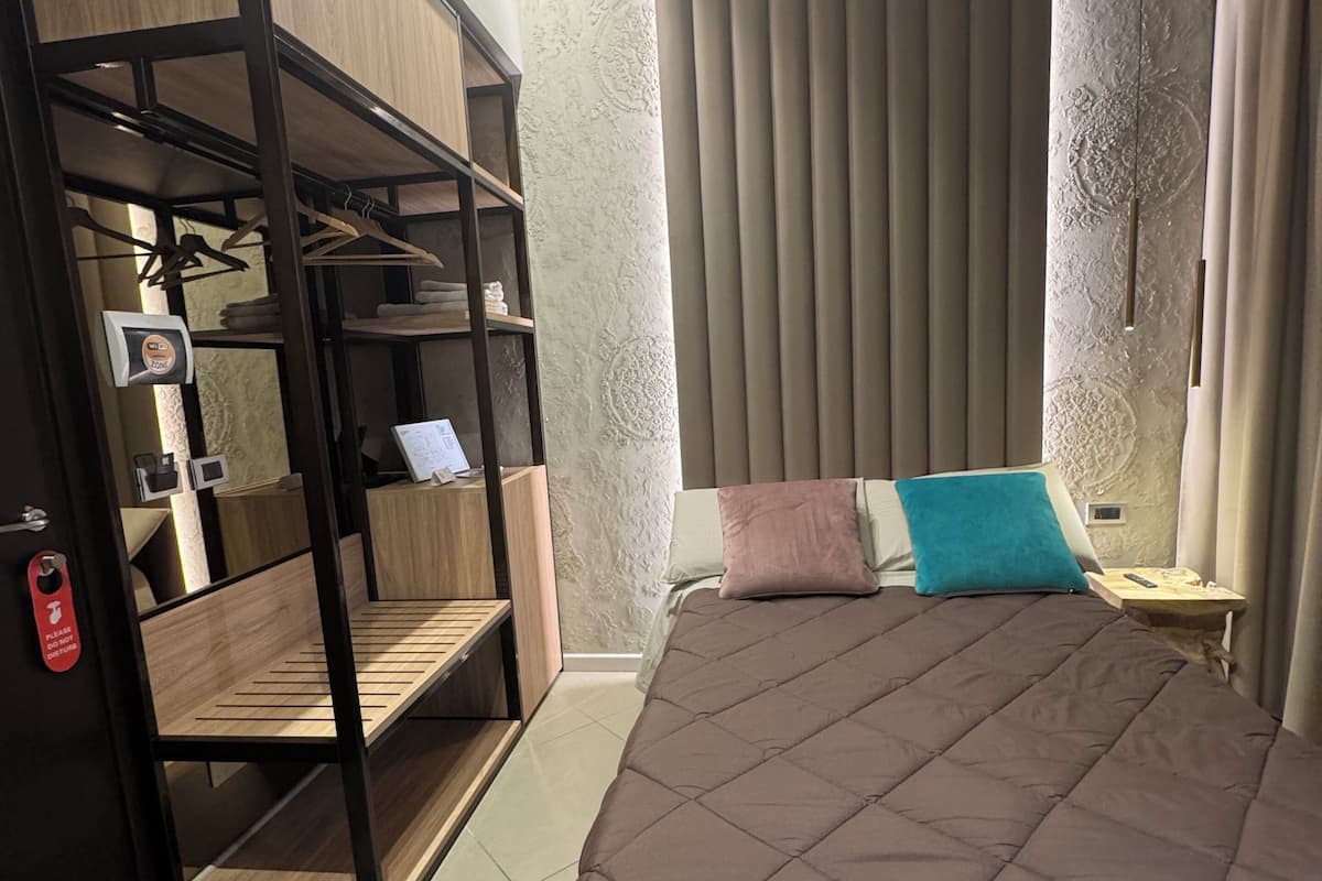 Une chambre moderne avec un grand lit, une armoire intégrée avec des étagères et une table de chevet.