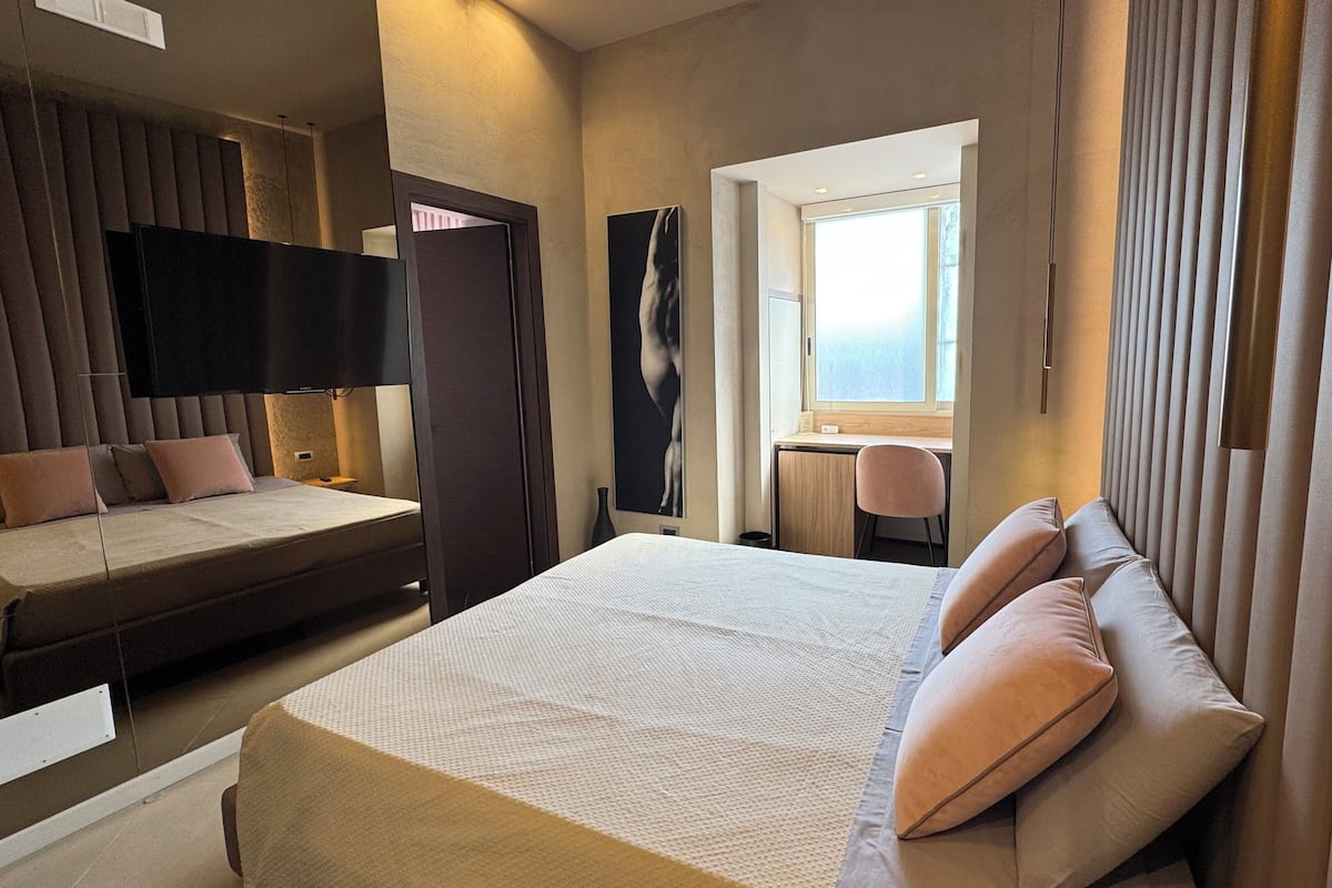 Une chambre d’hôtel avec un grand lit, un lit plus petit, un bureau et une fenêtre.