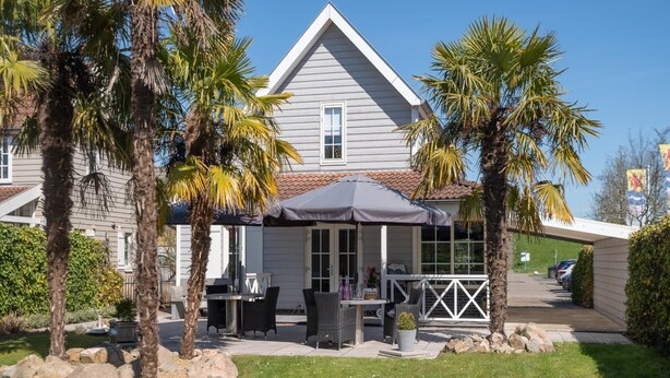 Une maison dotée d’un patio aménagé avec du mobilier d’extérieur et un espace salon couvert.