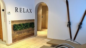 Ein Wellnessbereich mit einem 'RELAX'-Schild, einer Holzvertäfelung mit Grünpflanzen und einem gefliesten Boden.