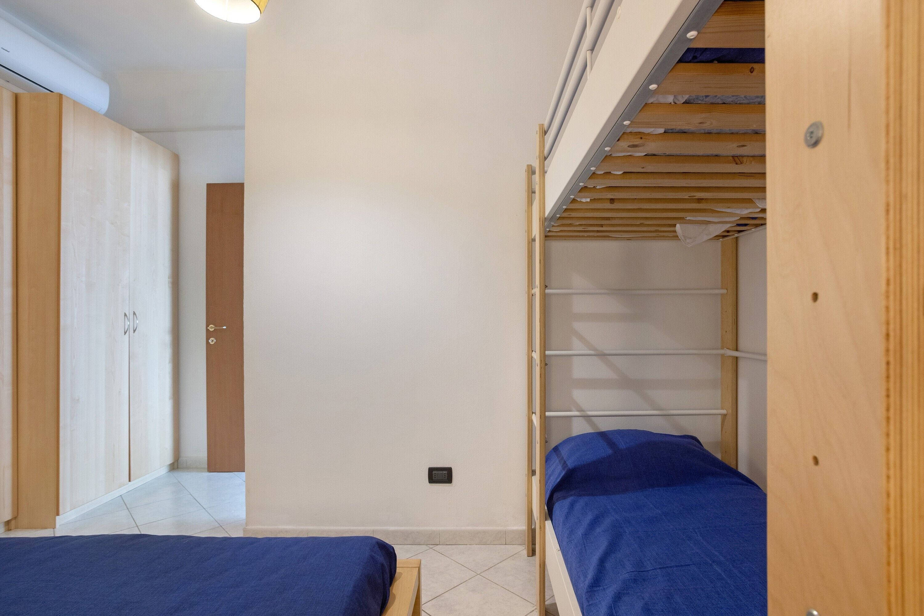 A room with a bunk bed, a wardrobe, and a small table.
