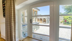 A white door with multiple glass panes leading to an outdoor area with a stone wall and a wooden structure.