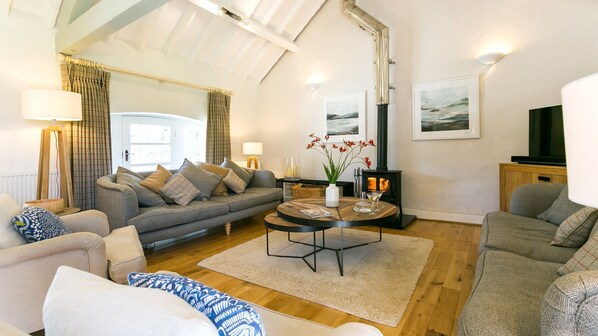 A cozy living room with a sofa, armchairs, a coffee table, and a fireplace.