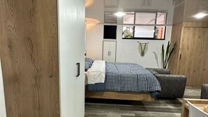 A compact bedroom with a bed, wardrobe, and a small desk area. - Loft studio apartment (Envigado)