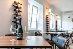 Interior de restaurant amb una botiga de vi, una ampolla de xampany Taittinger i dues copes sobre una taula.