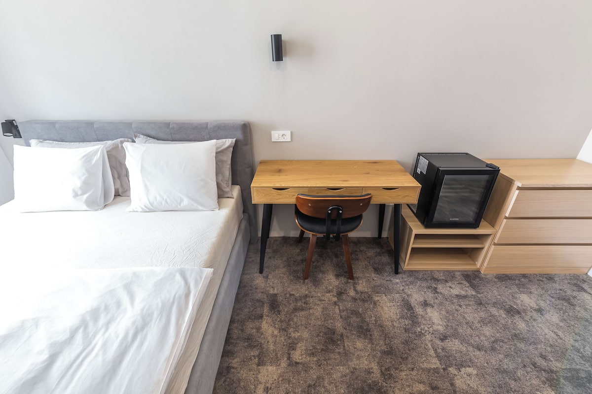 A bedroom with a bed, a desk, a chair, a TV, and a wardrobe.