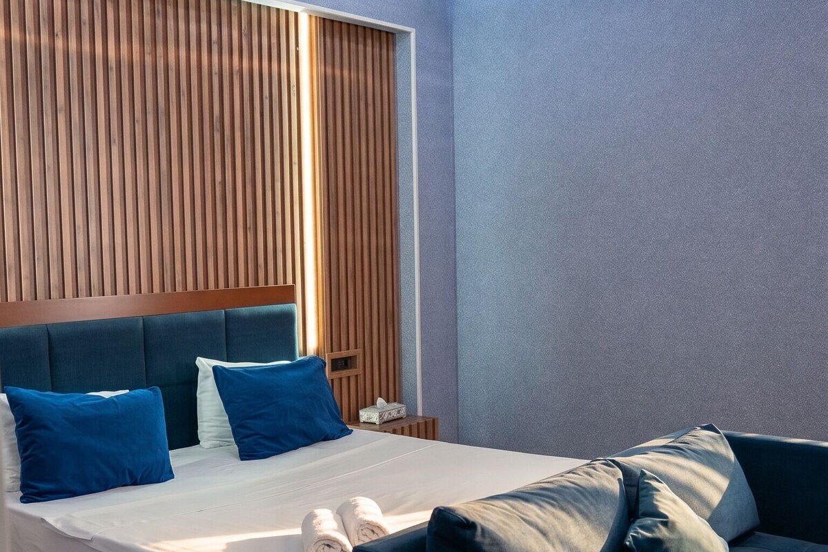 Un dormitorio moderno con cama, sofá y un techo de diseño único.
