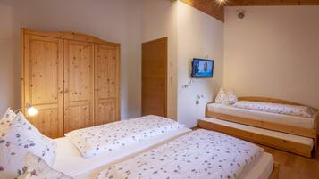 Ein Schlafzimmer mit zwei Betten, einem Holzschrank und einem Fernseher an der Wand.