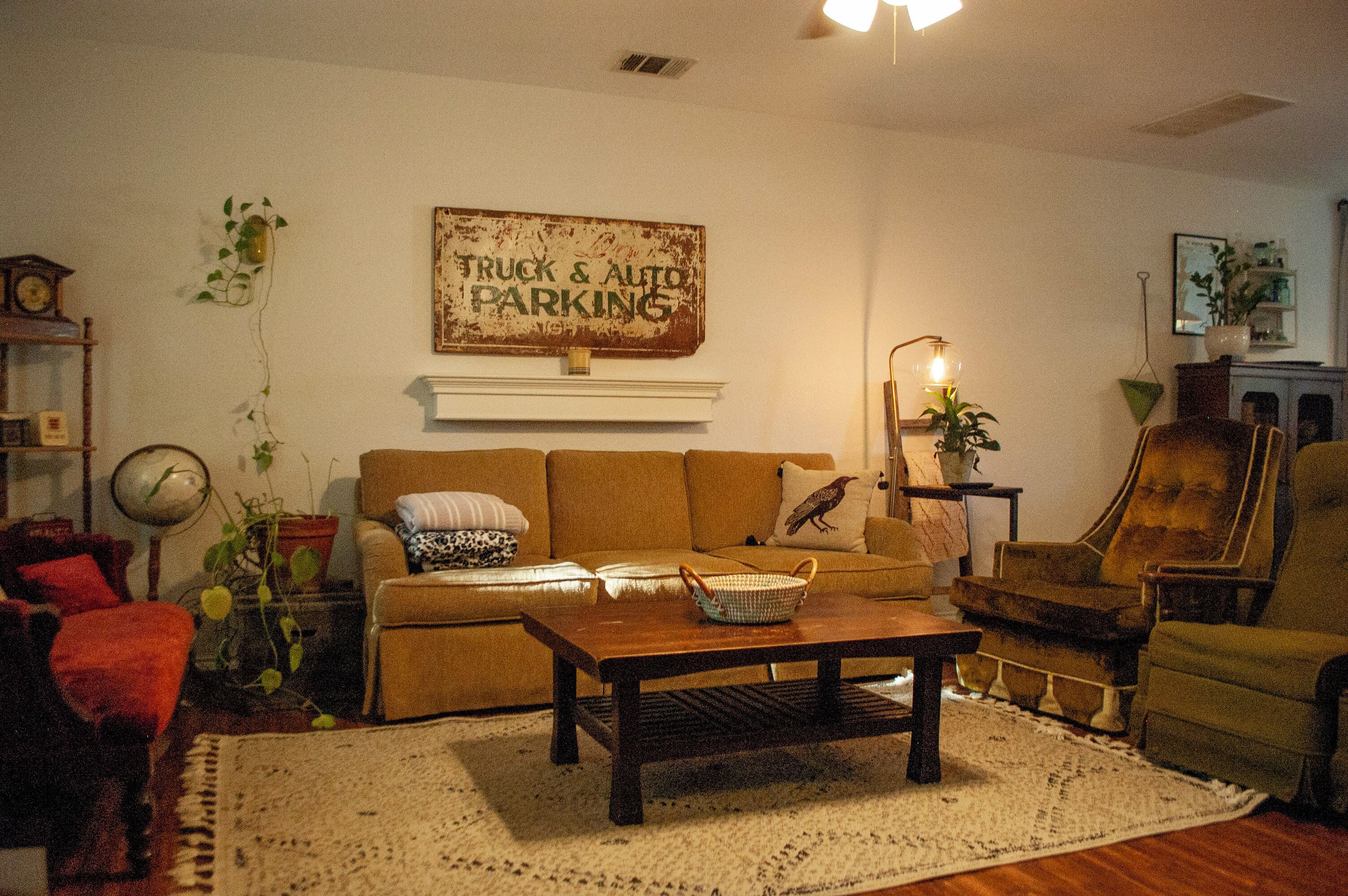 A cozy living room with a sofa, armchairs, a coffee table, and a 'Truck & Auto Parking' sign on the wall.
