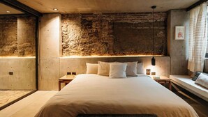Een moderne slaapkamer met een groot bed, een stenen muur en een hanglamp.