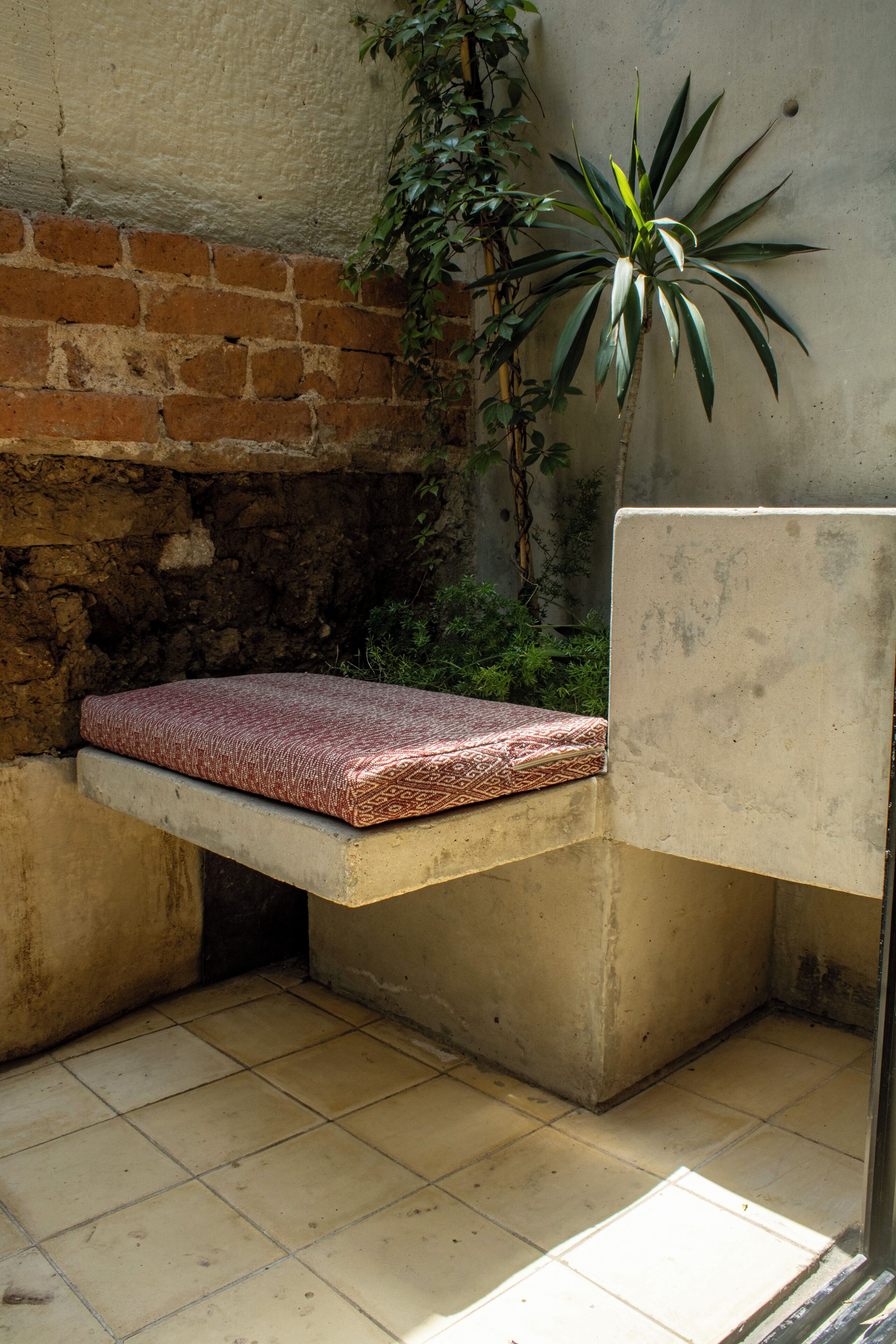 A small, enclosed outdoor seating area with a bench and a potted plant.