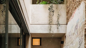 Een modern interieur met een betonnen bank, een glazen deur en potplanten.