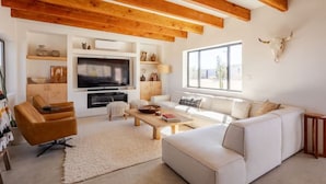 Ein modernes Wohnzimmer mit einem weißen Sofa, einem Holztisch und einem Fernseher.