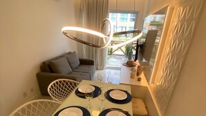 Ett modernt matområde med ett glasbord för fyra personer, en soffa och en hängande lampa.