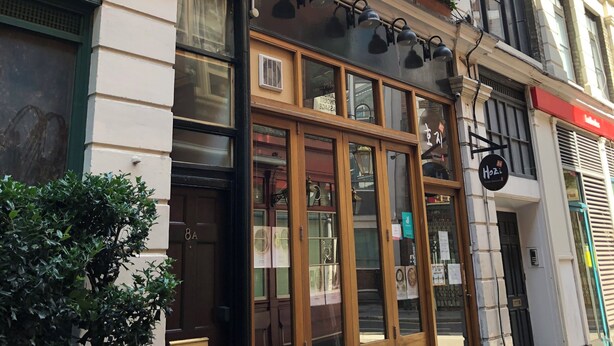 A building with a large window, a door with a sign, and a sign above the door.