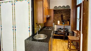 A compact kitchen with a central island, wooden beams, and a stone wall backsplash.