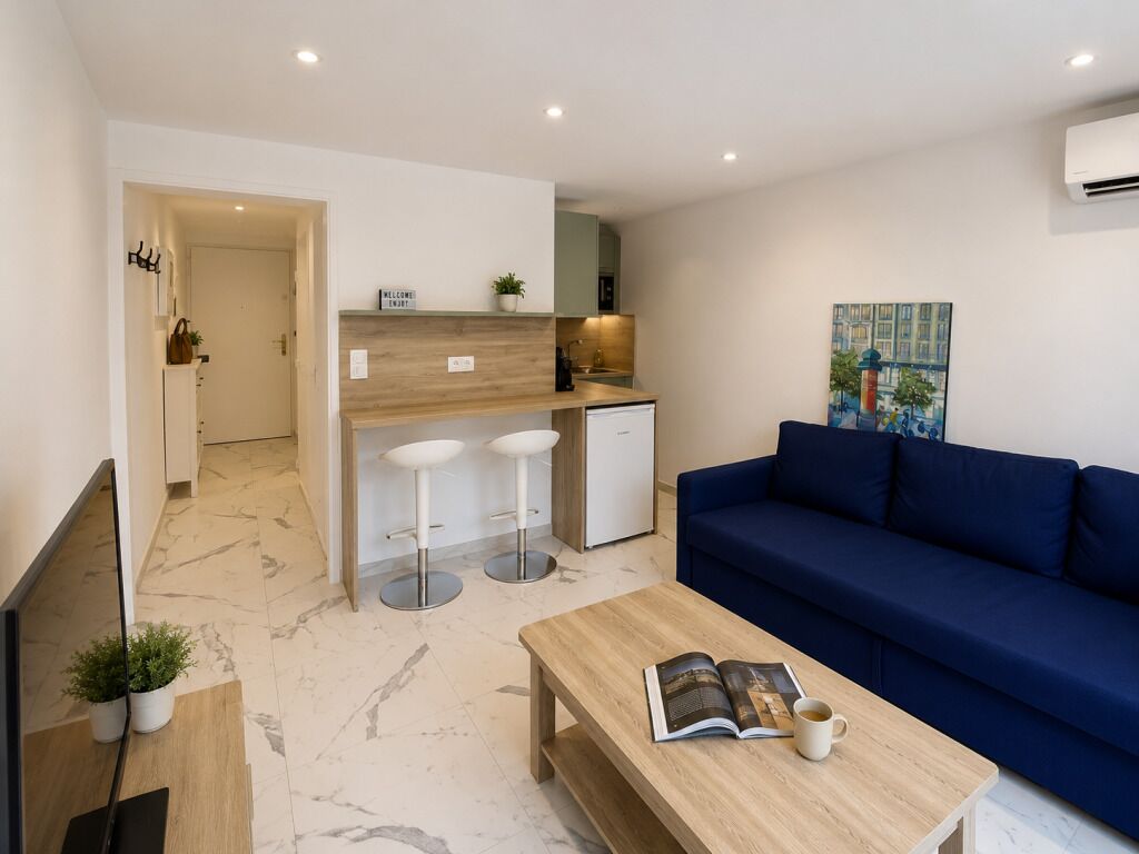 A modern living space with a sofa, a coffee table, and a kitchen area with stools.